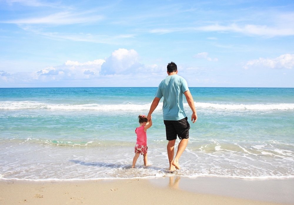 The Impact of EMF on Male Fertility and How Shielding and Grounding Can Help 7 Father holding his young child's hand while walking along a beach, illustrating family wellness in a Redemption Shield article about male fertility and EMF exposure.