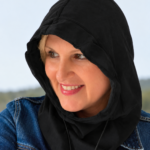 Woman wearing a black EMF protection shielding hood and blue denim jacket outdoors