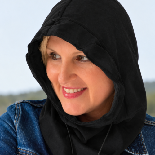 Woman wearing a black EMF protection shielding hood and blue denim jacket outdoors
